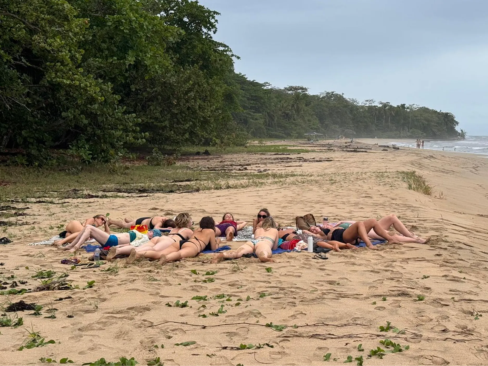 Skupina žensk leži v krogu na peščeni plaži